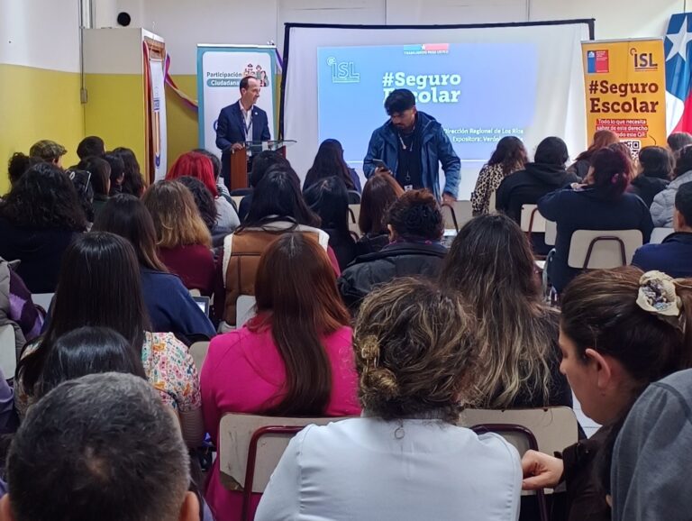 Personas sentadas en una sala reciben una capacitación sobre el Seguro Escolar del ISL, mientras un expositor presenta contenidos frente a una pantalla.