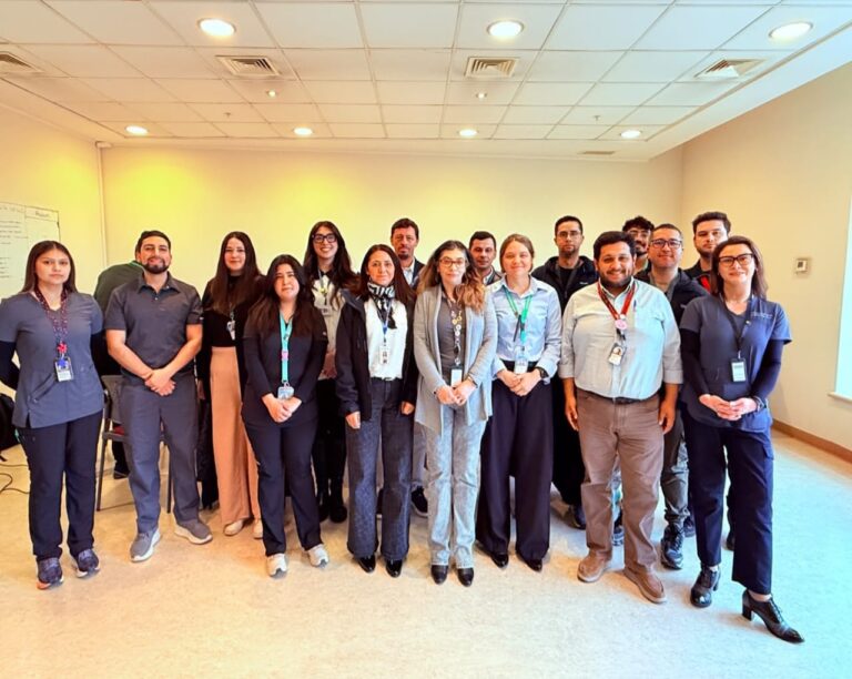 Fotografía grupal de trabajadoras y trabajadores de distintas instituciones, reunidos de pie al finalizar una jornada de trabajo en una sala de reuniones.